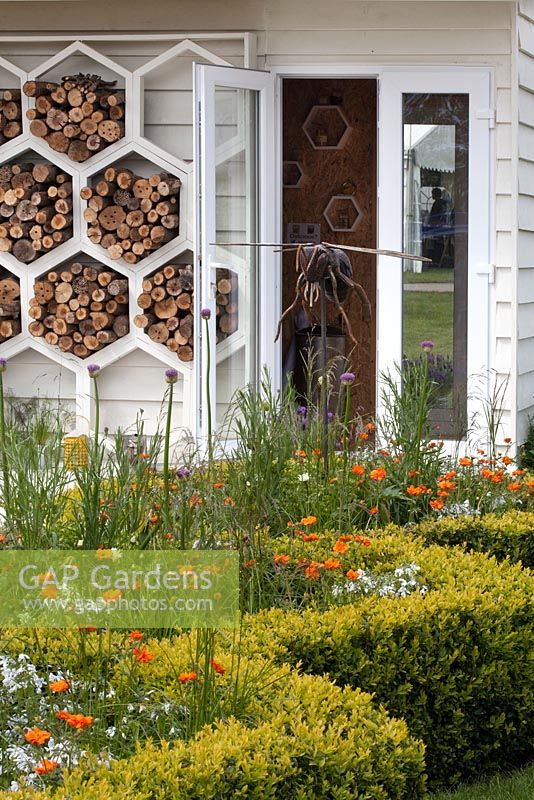 Le jardin des abeilles à l'appui du Bumblebee Conservation Trust, Malvern Spring Gardening Show 2015. Magasin de bois en forme de ruche et couverture de boîte, et plantes pour les pollinisateurs comme le Geum orange 'Totally Tangerine'