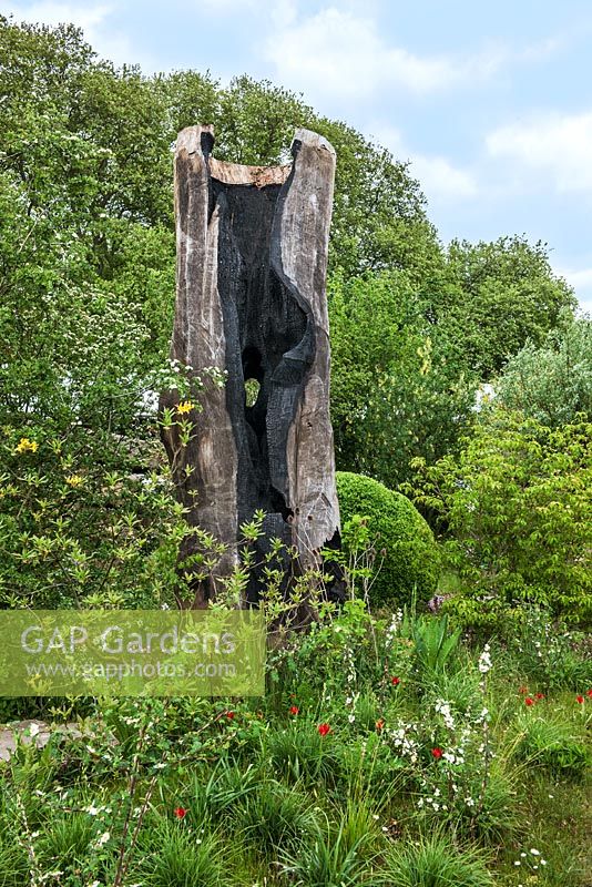 Le jardin Laurent-Perrier Chatsworth. Sculpture de tronc d'arbre brûlé, cardères, chêne anglais, tulipes et merle en lambeaux.
