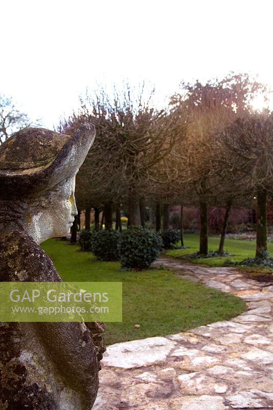 La sculpture de Simon Verity, The Lady, regarde vers le chemin pavé fou et la ruelle d'arbres