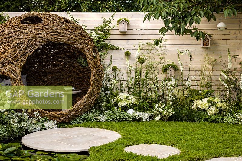 Paysages vivants «City Twitchers» - vue montrant des zones pavées circulaires, pelouse de camomille, étang, peau d'oiseau de saule sphérique, nichoirs et plantation mixte en blanc - RHS Hampton Court Flower Show 2015