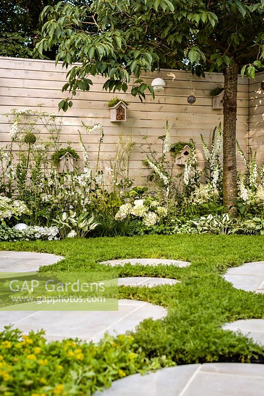 Paysages vivants 'City Twitchers' - vue montrant les zones pavées circulaires, la pelouse de camomille, les nichoirs, le prunier et la plantation mixte de blanc - RHS Hampton Court Flower Show 2015