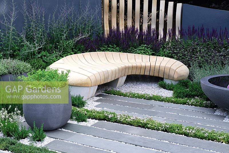 Jardin urbain avec banc en chêne sculpté et blanchi et pots en pierre grise sur un patio en pierre polie - Paysage vivant: guérison Jardin urbain - RHS Hampton Court Palace Flower Show 2015