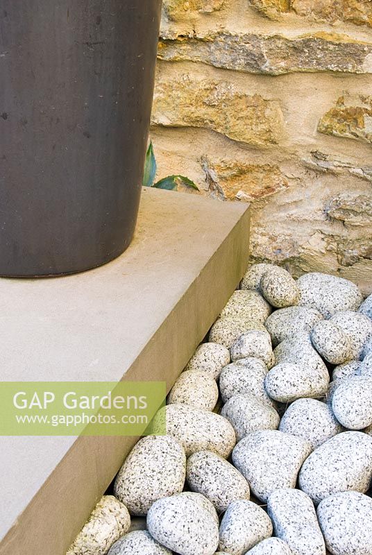 Jardin de la cour contemporaine conçu par Amir Schlezinger. Surfaces dures contrastantes - vieux mur de pierre, nouvelles marches en pierre, galets et pot noir. Jardin privé, Dorset, UK