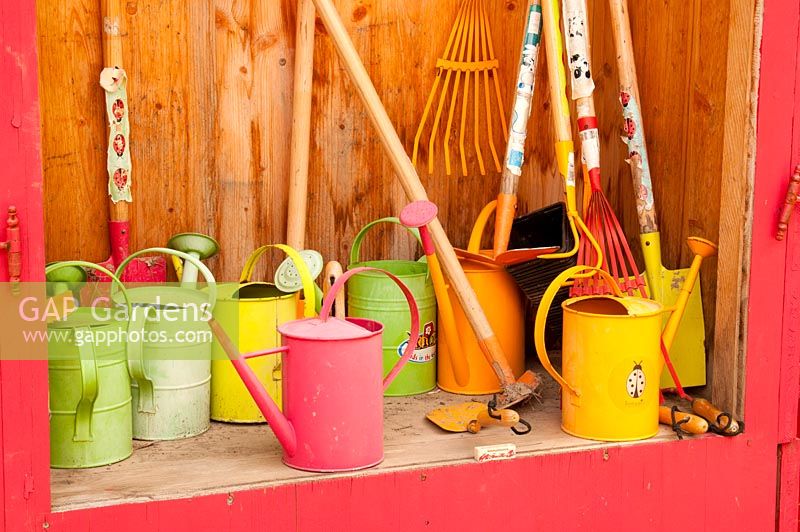 Ranger le matériel de jardinage pour enfants, y compris truelles, râteaux, bêches et arrosoirs