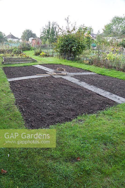 Une grande partie d'un lotissement alloué à un jardin de coupe. Les matériaux requis sont des étiquettes de plantes de noisetier, des ficelles, des râteaux, des tubercules, des bulbes et des graines.