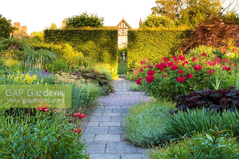 Les couleurs chaudes du jardin Lanhydrock, avec vue sur la maison, au Wollerton Old Hall Garden, Shropshire. La plantation comprend: Ligularias, roses, Alstroemerias et Achilleas.