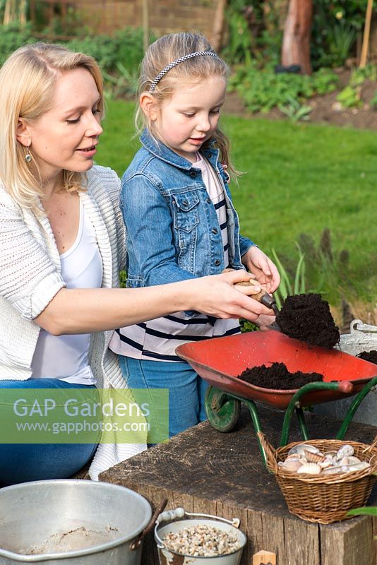 Enfant plantant une brouette jouet avec des plantes succulentes. Remplissez la brouette de compost.