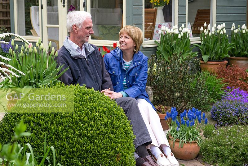 Tony et Julie Peckham dans leur jardin de la fin du printemps, assis sur les marches devant un nouveau pavillon d'été.