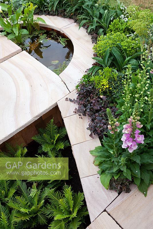 Parterre de jardin en grès coulé avec des bords incurvés et un élément d'eau semi-circulaire.