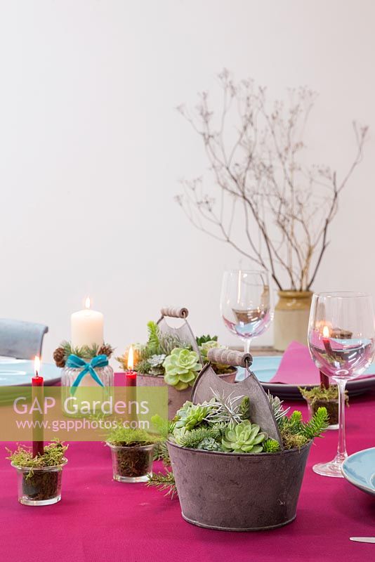 Set de table avec plantes succulentes dans des pots en métal et des bougies rouges montées en mousse