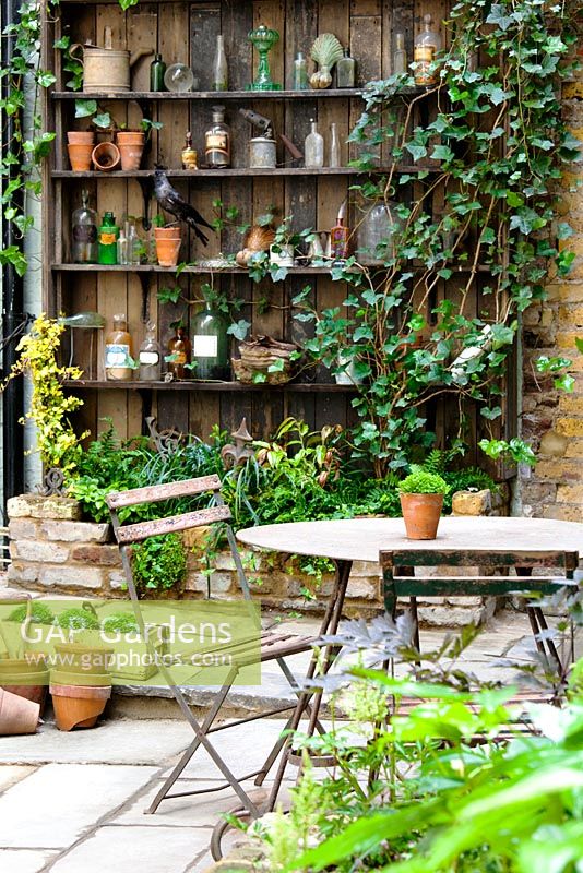 Vue sur cour avec table et chaises aux étagères avec des objets. Lucille Lewins, petit bureau cour jardin dans Chiltern street studios, Londres. Conçu par Adam Woolcott et Jonathan Smith juin 2010, Royaume-Uni