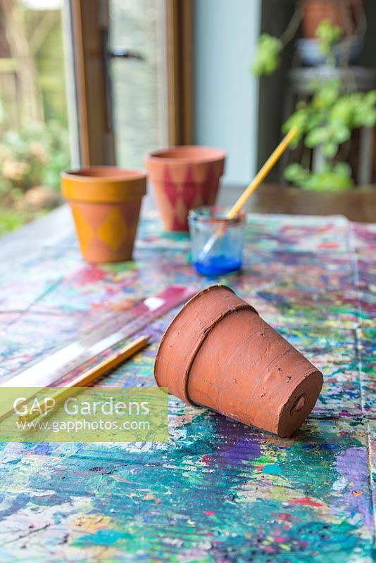Les matériaux requis sont une règle, un crayon, des pots en terre cuite, un pinceau et de la peinture