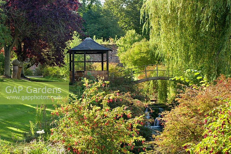 Jardin clos, Cambo, Fife, Scotland, UK. Fuchsia par brûlure avec pont voûté et pavillon