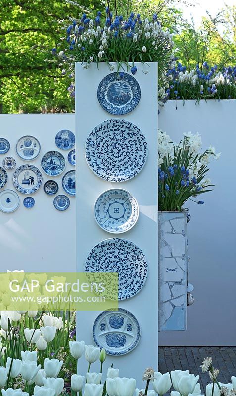 Toutes sortes de motifs conçus par Delfts Blue sur des plaques suspendues à un mur. Muscari blanc et bleu, tulipes blanches et narcisse. Jardin d'inspiration: Delfts Blue.