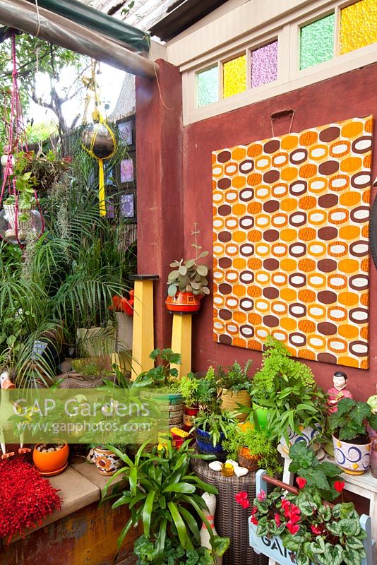 Le jardin du centre-ville avec des fougères, des cyclamens et des broméliacées présente des pièces rétro éclectiques colorées provenant des marchés locaux.
