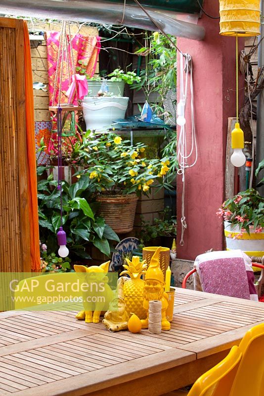 Le jardin du centre-ville avec des bégonias et des spathiphyllums présente des pièces rétro éclectiques colorées provenant des marchés locaux, y compris une salle à manger en bois avec des objets jaunes assortis