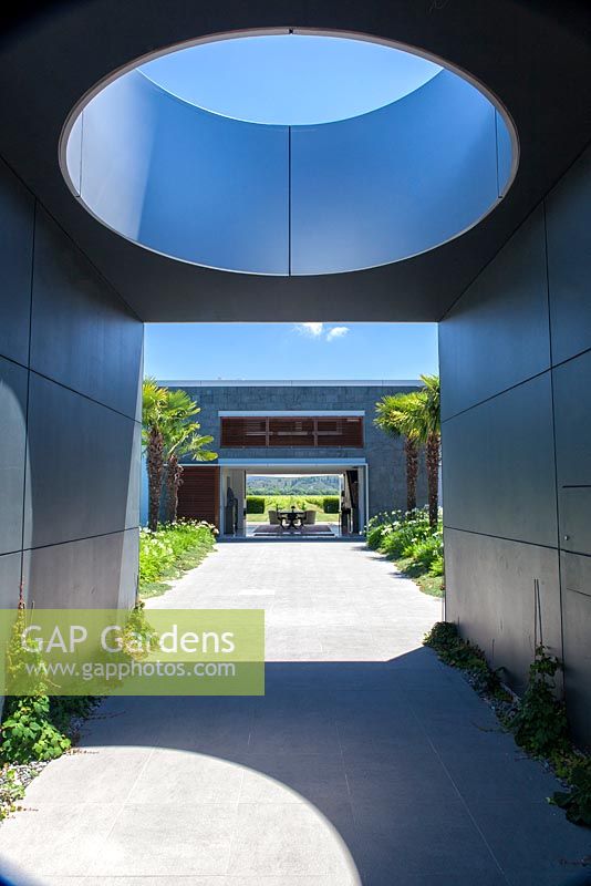 Oculus jette une ombre et une vue à travers la maison moderne sur les vignobles au-delà au jardin Bhudevi Estate, Marlborough, Nouvelle-Zélande.