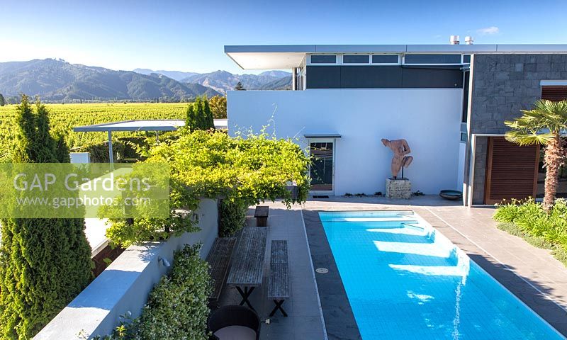 Maison et piscine avec chaîne de montagnes et vignobles au-delà au jardin Bhudevi Estate, Marlborough, Nouvelle-Zélande.