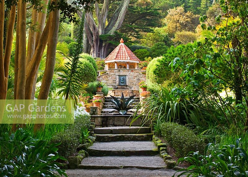 Vue sur le jardin méditerranéen avec marches, fontaine d'agave de Tom Leaper, fontaine murale et maison de coquille, jardin de l'abbaye de Tresco, Tresco, îles Scilly.