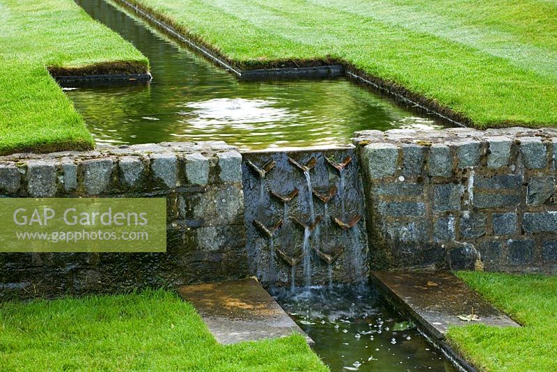 Détail d'un vol descendant de rigoles dans une pelouse engloutie, avec cascade d'eau. Poulton House Garden, Wiltshire.