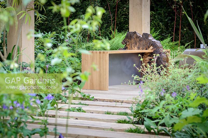 Un panneau en bois et un banc en chêne et un chemin en dalles de chêne dans The Garden of Potential. The RHS Chelsea Flower Show 2016 - Designer: Propagating Dan - Sponsor: GreenWood Forest Park - SILVER-GILT.