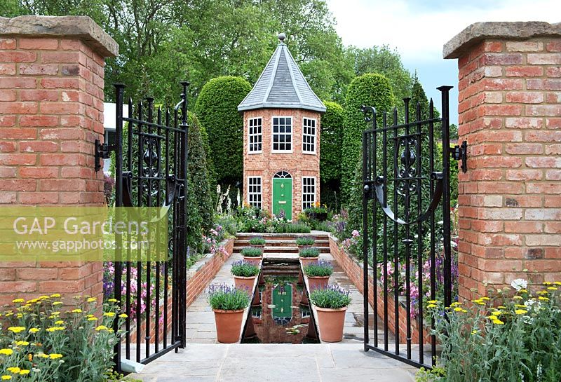 Le Harrods British Eccentrics Garden. Vue à travers les portes de la piscine, de la maison et des parterres de fleurs. RHS Chelsea Flower Show 2016, Designer - Diarmuid Gavin.
