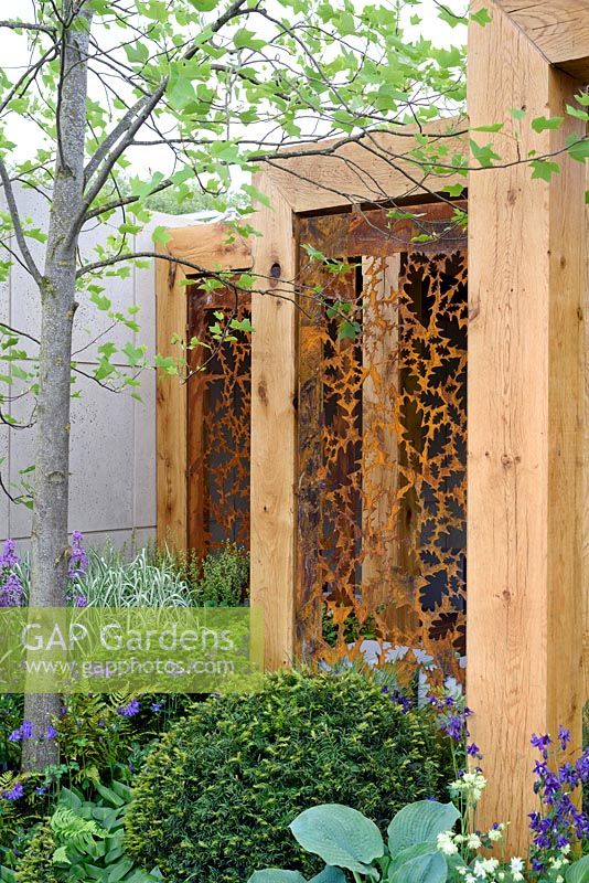 Paravent en métal rouillé au pochoir dans un cadre en bois. Le jardin Morgan Stanley pour l'hôpital Great Ormond Street. RHS Chelsea Flower Show 2016