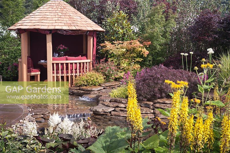 Un étang bordé de pierre naturelle et un kiosque en bois. Jardin: 'Reflections' au RHS Tatton Park Flower Show 2012