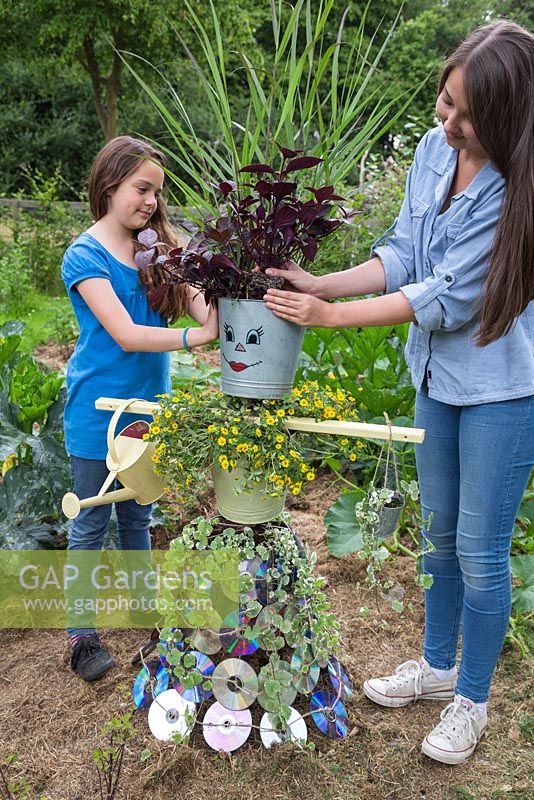 Deux jeunes filles plantant Iresine dans la tête de l'épouvantail