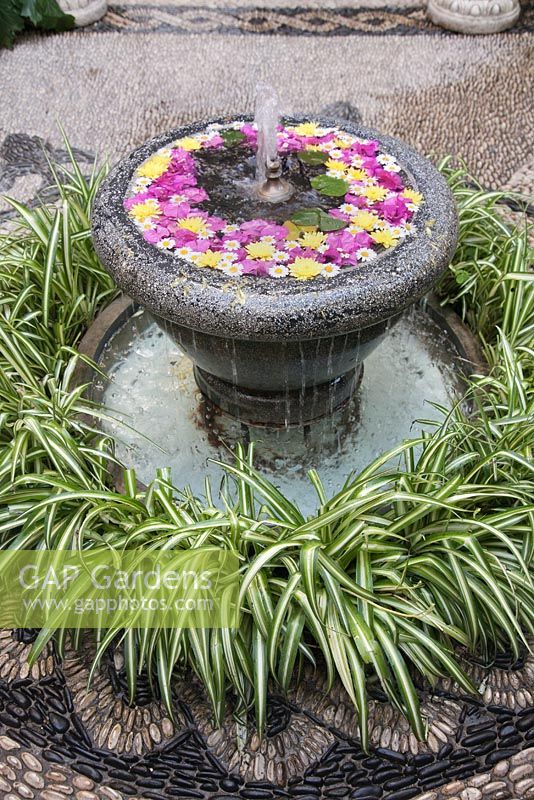 Fontaine d'eau remplie de fleurs en pierre grise dans la cour jardin avec mosaïque en pierre, Cordoue, Espagne