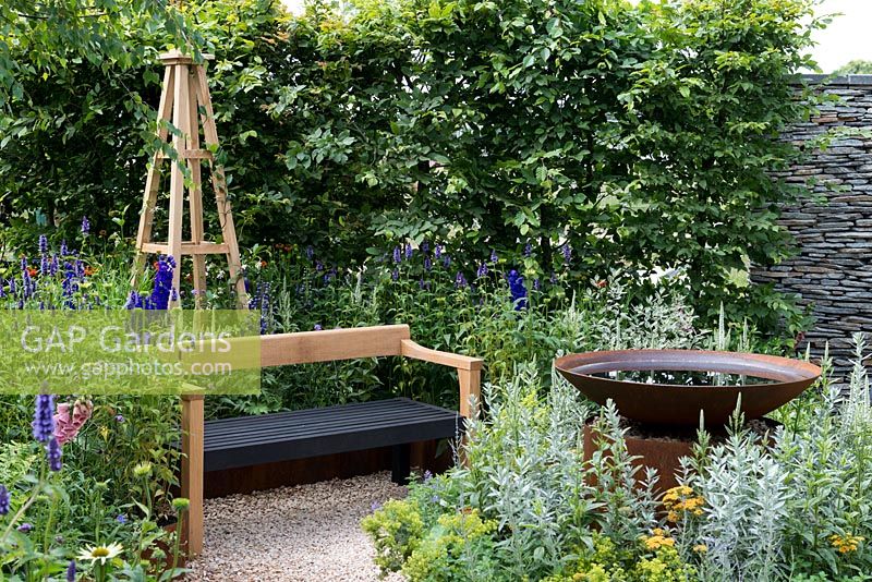 Une salle de jardin inspirée des arts et de l'artisanat avec un plan d'eau, une haie de charme et un banc artisanal entouré de vivaces. Une retraite d'été conçue par Laura Arison et Amanda Waring. RHS Hampton Court Flower Show 2016