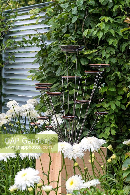 Une sculpture contemporaine en métal sur un socle en chêne. Un jardin de retraite conçu par Martin Royer. Exposition florale de Hampton Court