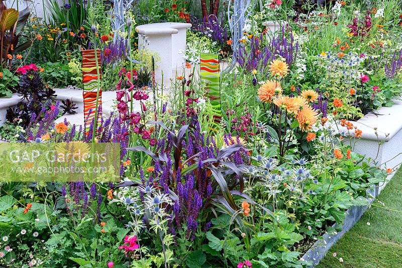 New Horizons City Garden. Panneaux en verre fondu coloré dans un parterre de fleurs orange, rouge et bleu. Designers: Beautiful Flowerbeds, Sponsors: Beautiful Flowerbeds Garden Design. RHS Hampton Court Palace Flower Show 2016