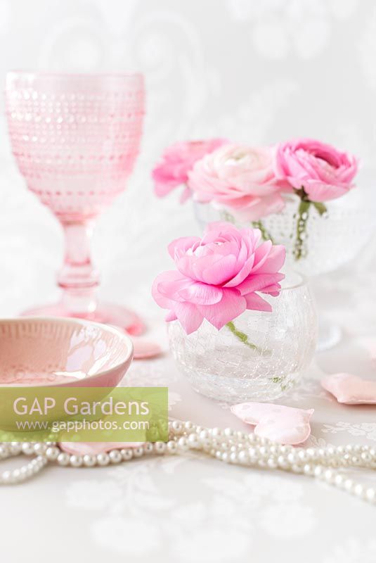 Renoncule rose dans des pots en verre dans un arrangement avec des coeurs et des perles