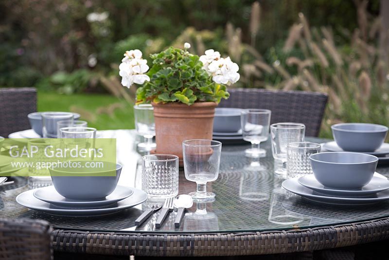 Ensemble de table à manger de patio prêt avec un pélargonium en pot comme pièce maîtresse
