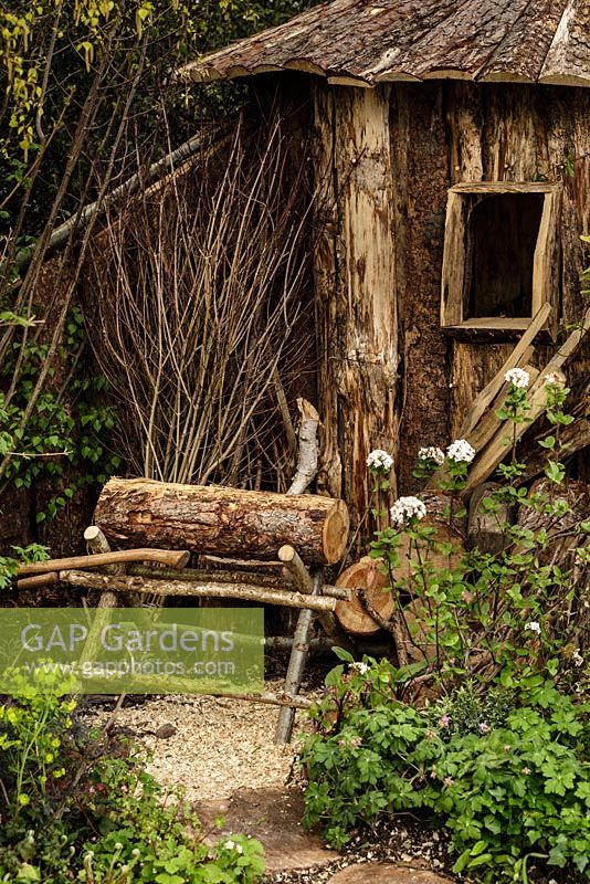 Cabane en bois rustique, cheval de scie, grumes et plantation de bois - The Woodcutter's Garden - RHS Malvern Spring Show 2016. Concepteur: Mark Walker, commanditaire: Howards Motors