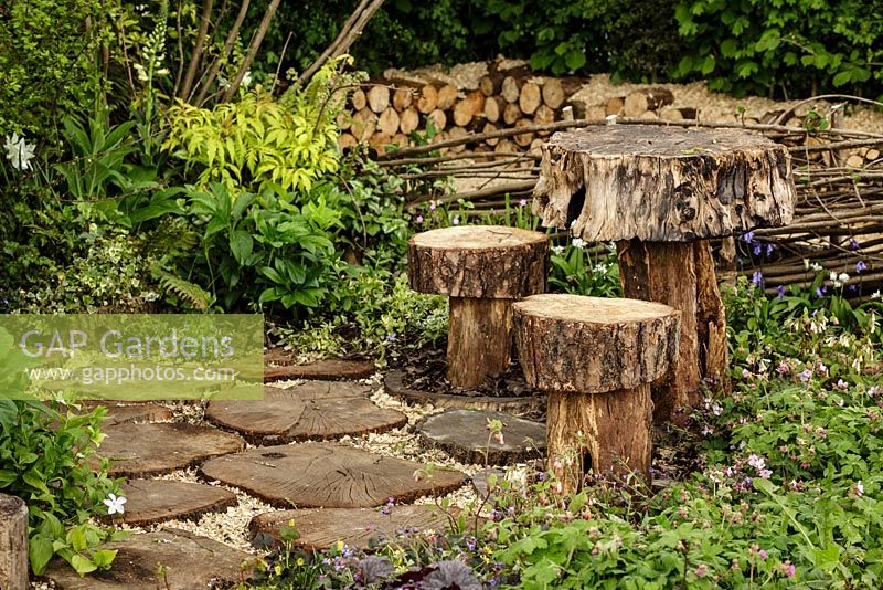 Tremplins, table et tabourets fabriqués à partir de troncs d'arbres entourés de plantations de bois - The Woodcutter's Garden - RHS Malvern Spring Show 2016. Concepteur: Mark Walker, commanditaire: Howards Motors