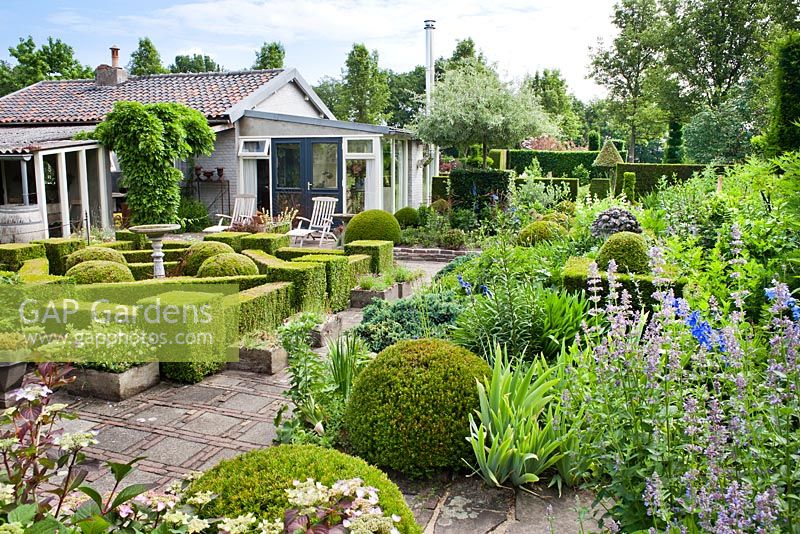 Jardin à la française avec parterres de fleurs vivaces, topiaire et haie. Jardin Frank Thuyls.