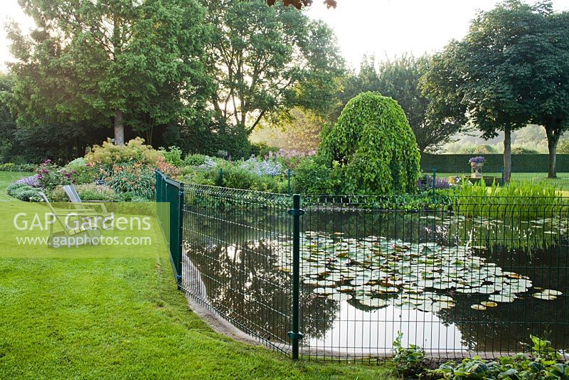 Fauteuils inclinables près de l'étang avec petite clôture de sécurité pour les enfants. Jardin Yvan et Gert En Belgique.