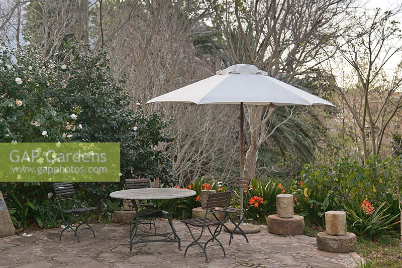Table et chaises en bois et métal en plein air avec parasol blanc sur la terrasse avec Camellia et Clivia miniata - Septembre, l'hôtel Vineyard, Cape Town, Afrique du Sud