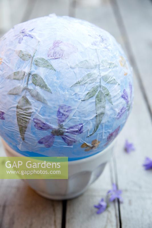 Fabrication de lanternes en papier - Une fois que vous avez terminé d'appliquer les fleurs, mettez une dernière couche de papier de soie sur toute la lanterne à fleurs et laissez sécher complètement. Éclatez le ballon et retirez-le du bol. Enfilez du fil si vous allez le suspendre.