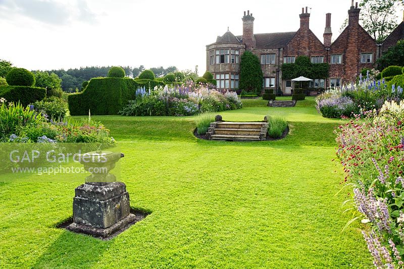 Les parterres de plantes herbacées devant la maison comprennent les knautias, les delphiniums, la gale et les achillées. Felley Priory, Underwood, Notts, Royaume-Uni