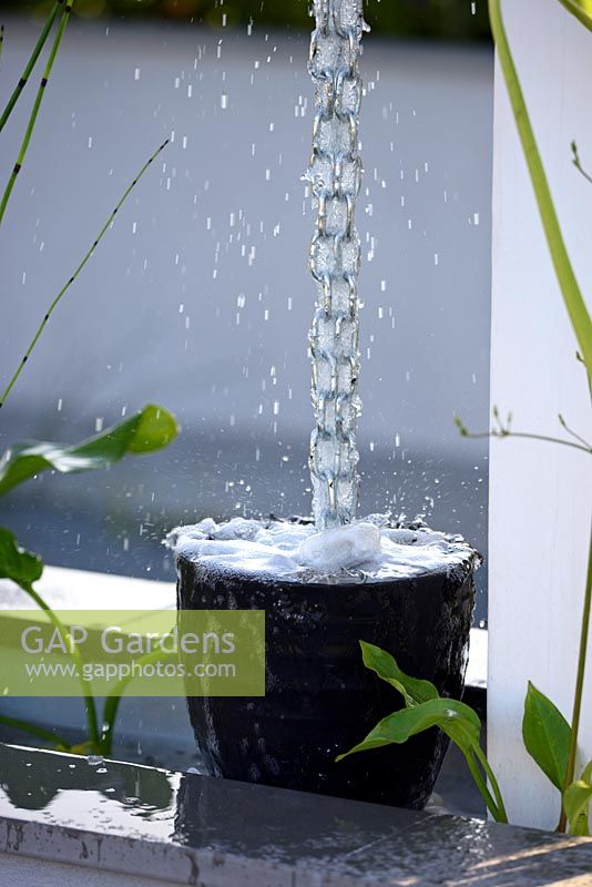 Le jardin Urban Rain. Chaîne de pluie suspendue dans un pot de galets dans un jardin contemporain. Conception: Rhiannon Williams, sponsors: Landform. RHS Hampton Court Palace Flower Show 2017