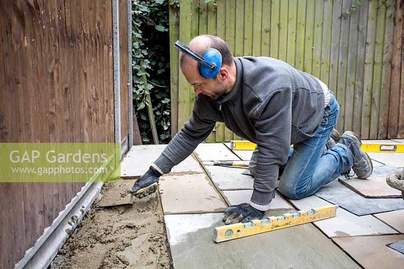 Niveler le ciment avec une truelle avant de poser un pavé en pierre sur le patio
