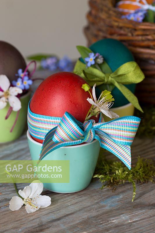 Oeufs de Pâques teints décorés avec ruban, fleurs délicates et ficelle