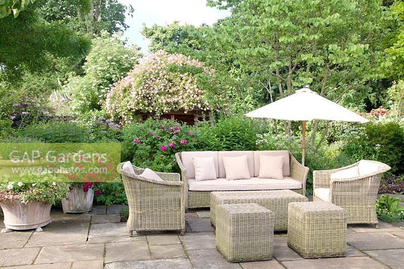 Meubles en osier sur terrasse en été avec Rosa et pots décoratifs mixtes