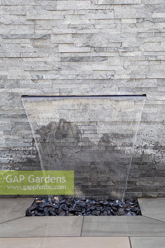 Dispositif d'eau mural et revêtement en pierre dans un jardin moderne