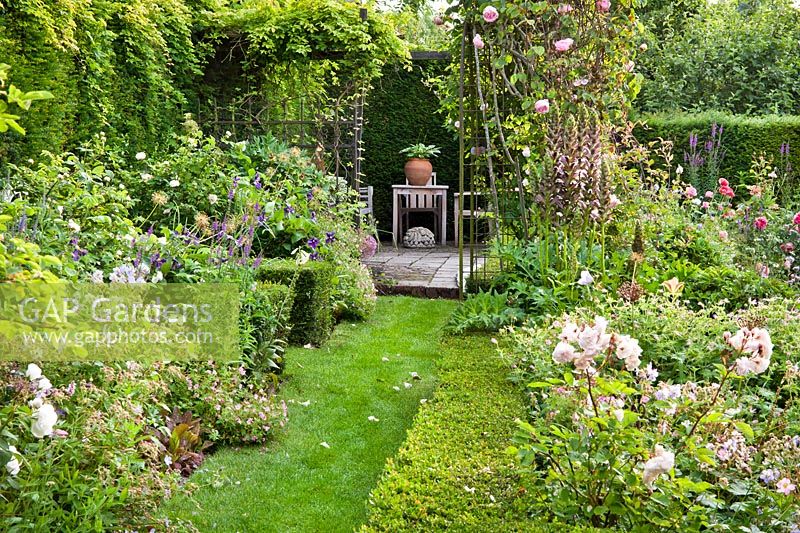 Chemin d'herbe entre les parterres de plantes vivaces et de roses menant au patio - Hetty van Baalen garden, Pays-Bas