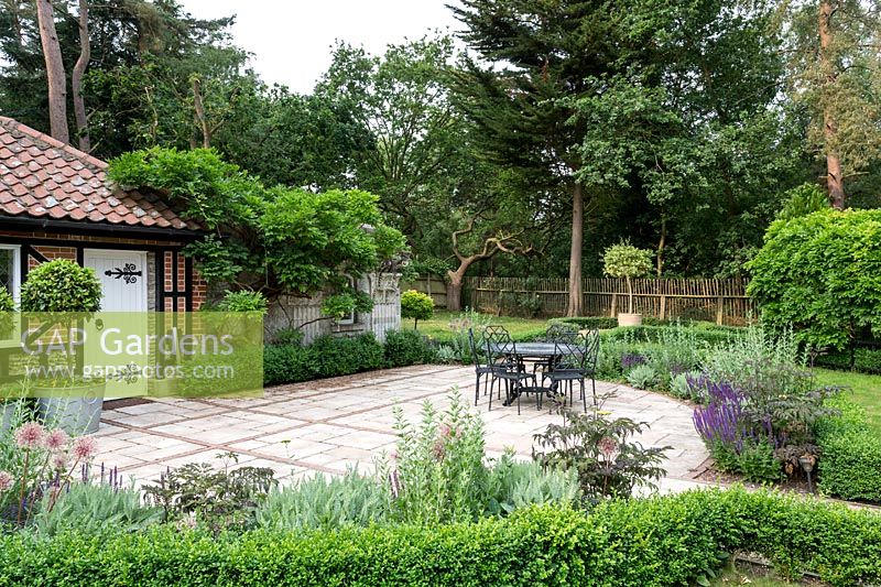 Gatehouse avec Buxus sempervirens haie bordant un patio dans un jardin conçu par Tom Hoblyn à Heatherbrae