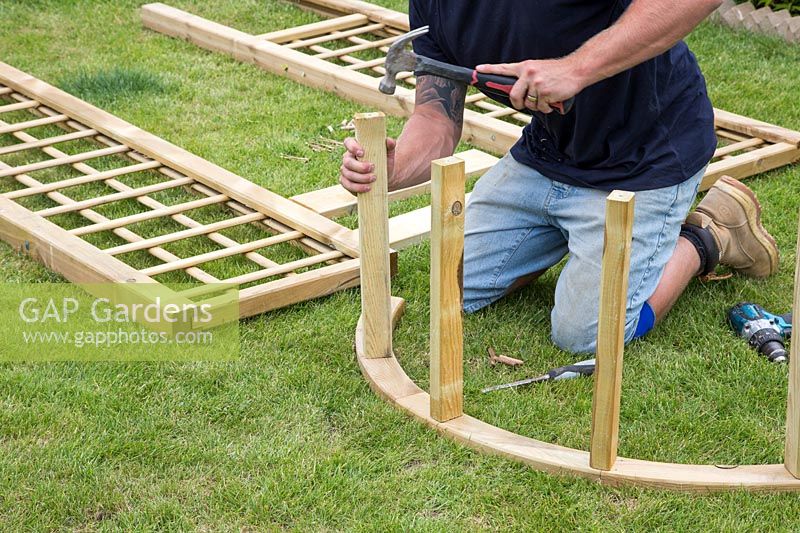 Faire une arche - Homme utilisant un marteau pour fixer les entretoises en bois dans l'arche